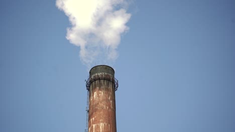 close up of industrial chimney with emission on the background of a clear blue sky