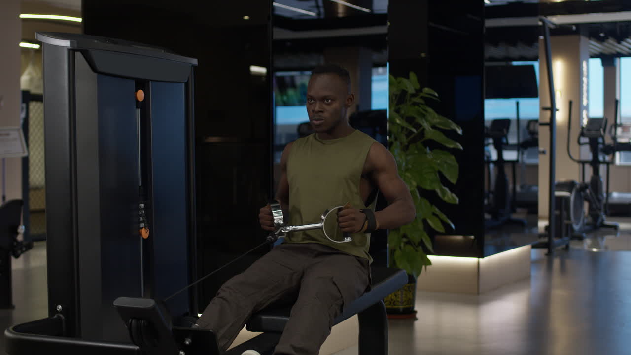 Man Working Out on a Seated Row Machine in a Modern Gym