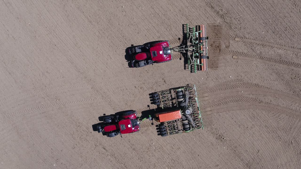 Aerial zenithal shot of tractors lined up and ready on dry farmland near Prague under sunlight