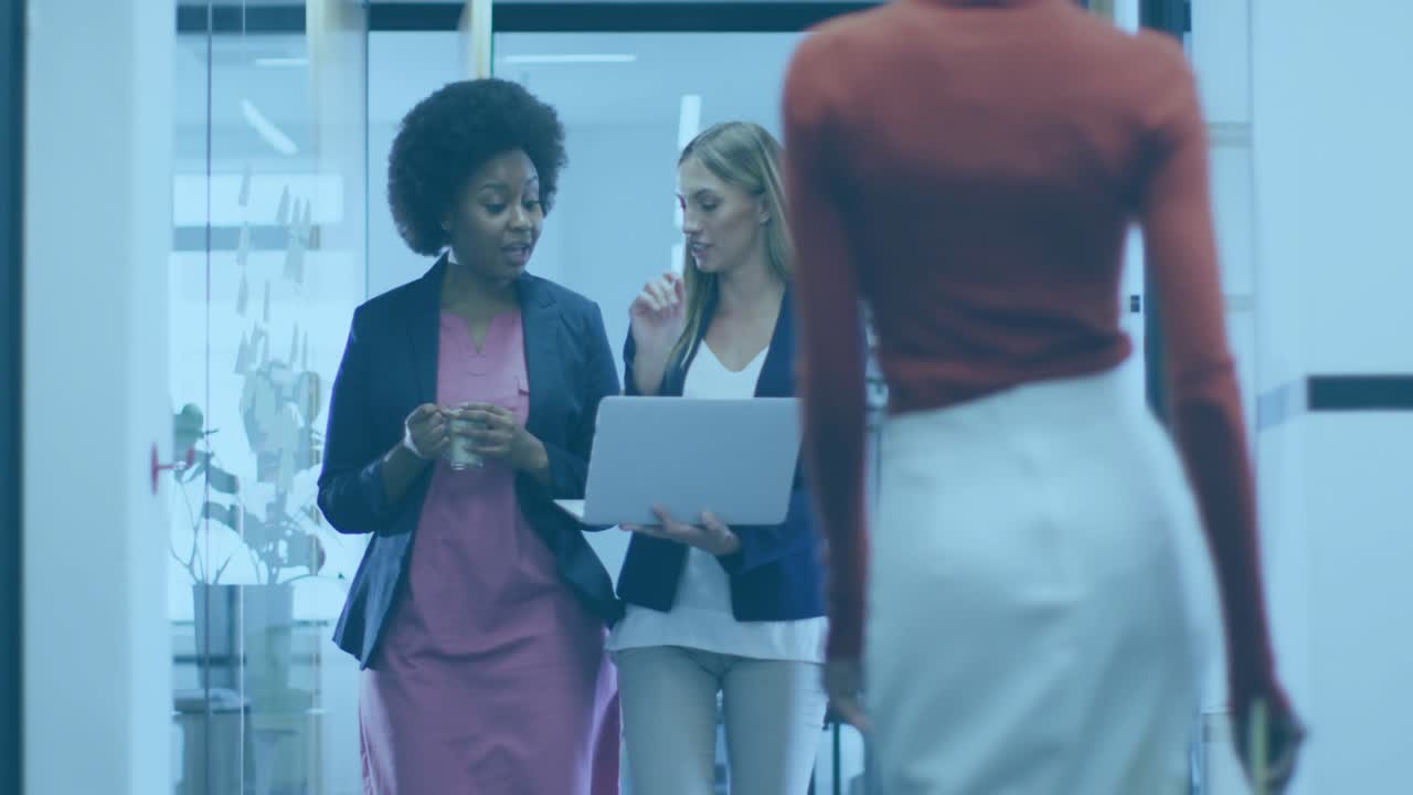 Two coworkers walking office, woman in red passing causing laptop user reviewing with code overlay