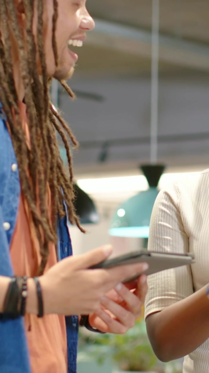 Vertical video: Showing man in blue shirt shifting tablet grip, sharing file at office, copy space