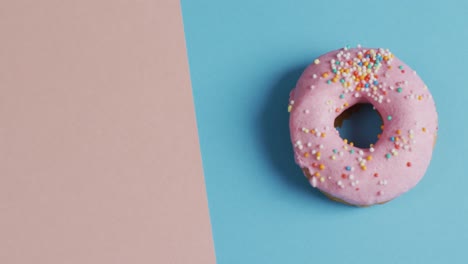 Video-of-donut-with-icing-on-blue-and-pink-background