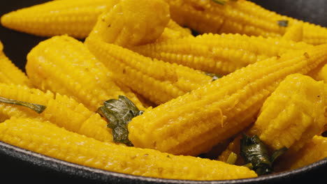 close-up of fermented yellow mini corn with black pepper on plate. preservation of vegetables in glass jars. fermentation preserved mini corns with spices macro.
