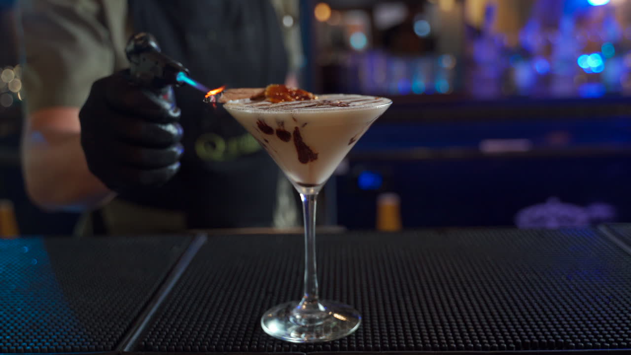 barista che fuma cocktail alla cannella fiammeggiante con la torcia