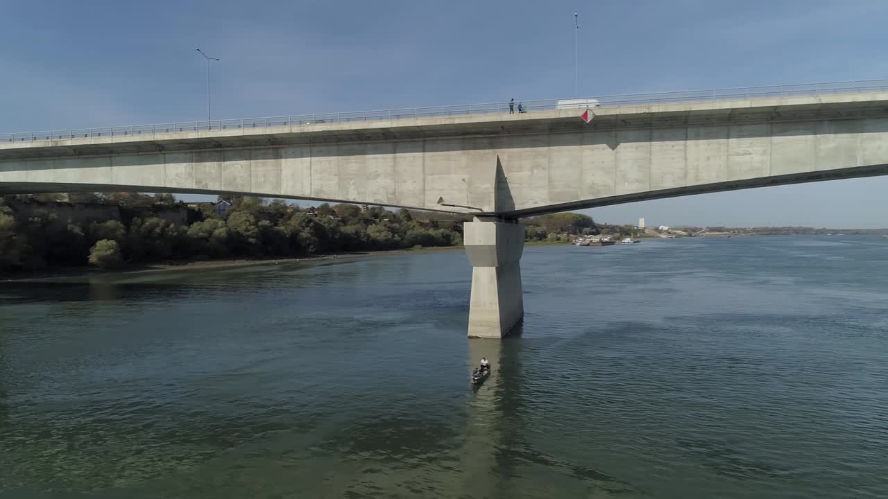 화창한 날 베오그라드, 제문, 작은 배 아래에 있는 일부 어부들의 다뉴브 강을 가로지르는 대형 콘크리트 다리를 보여주는 공중 hd 샷
