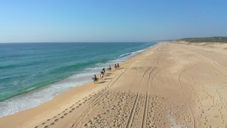 Vista-Aérea-De-La-Expedición-A-Caballo-En-La-Playa-Con-Gente-Irreconocible,-Melides-Portugal