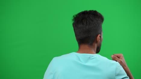 retrospectiva motivado hombre de oriente medio gestando animando para el equipo de fútbol en pantalla verde. joven entusiasta aficionado al deporte apoyando el juego en el campeonato en chromakey maqueta de fondo.