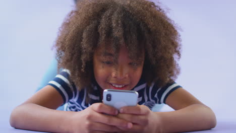 studio portrait of boy using mobile phone against purple background