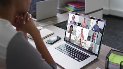 african american woman having a video conference on laptop with office colleagues at office