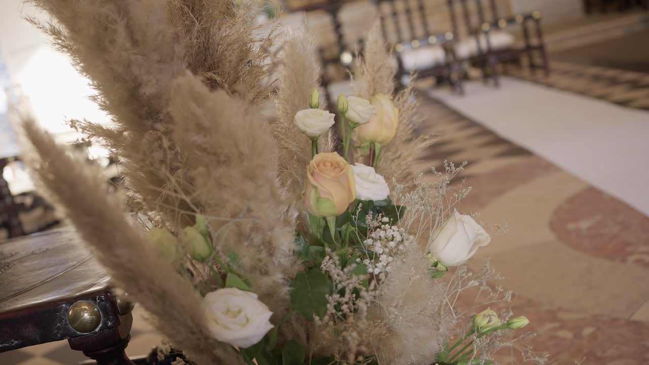 Close up of neutral wedding flowers and pampas grass aisle decoration