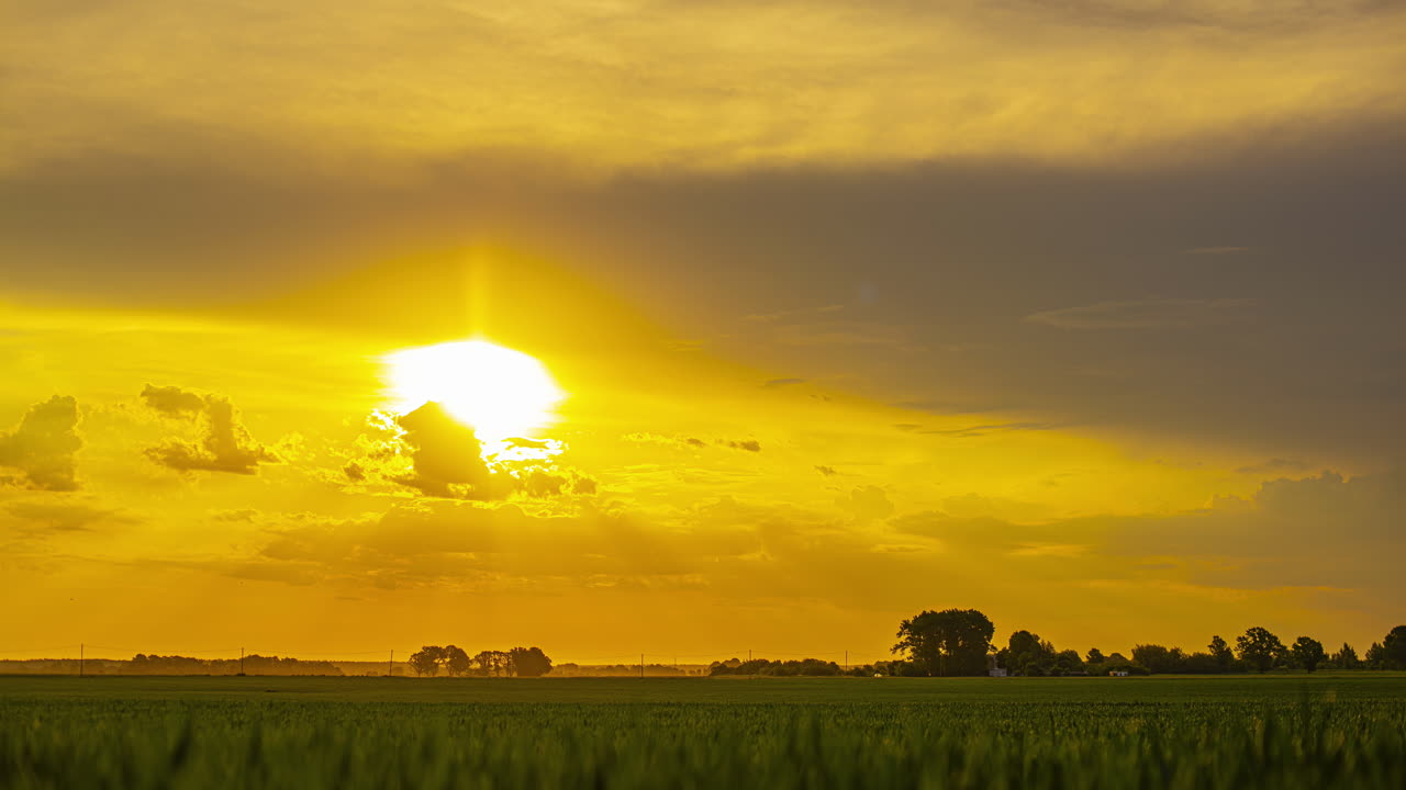 золотой восход солнца с теплым светом распространяется по спокойному и спокойному пейзажу с светящимися зелеными облаками над полями