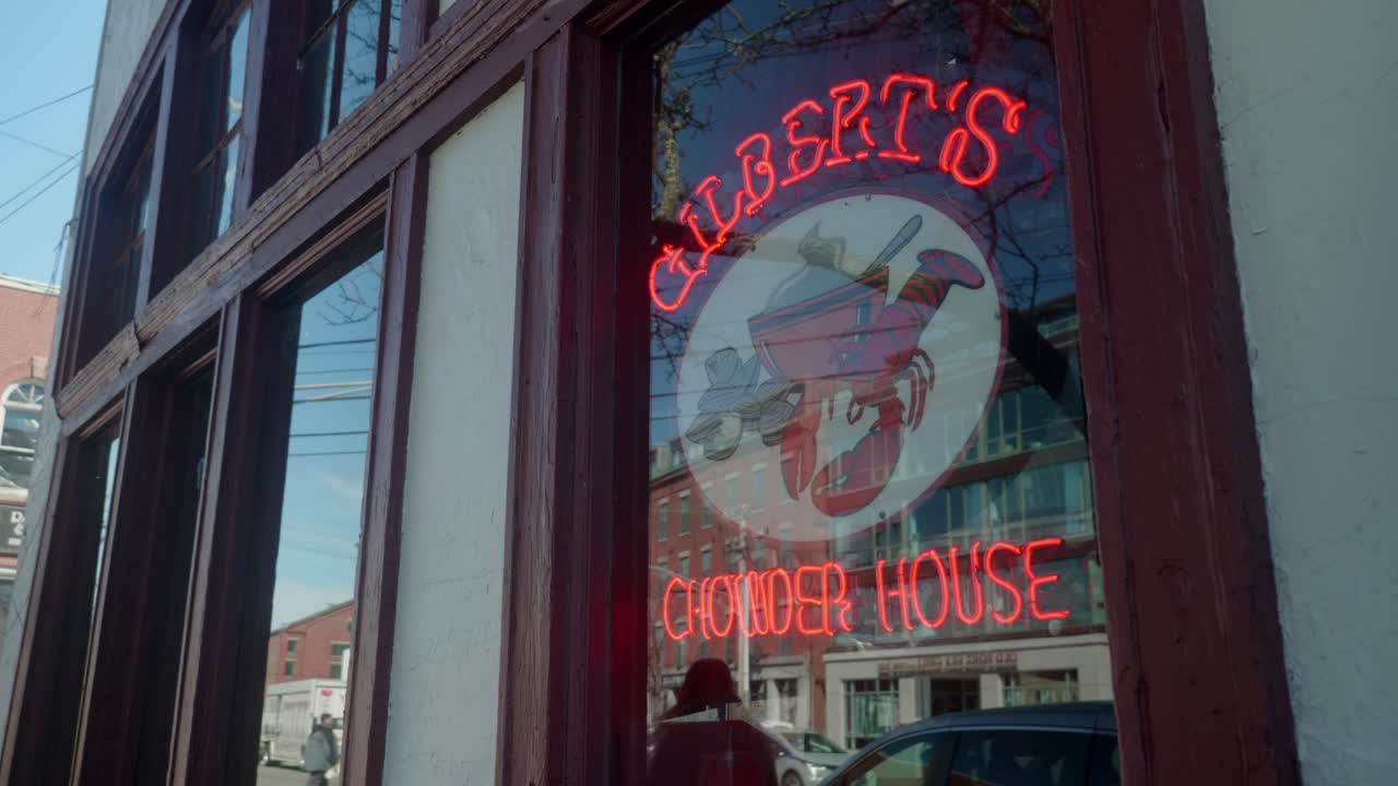 A charming street with historic building and vibrant neon sign of restaurant serving chowder in coastal city