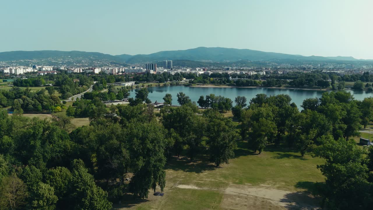 aerial view of Lake Jarun park with city skyline and mountain in background