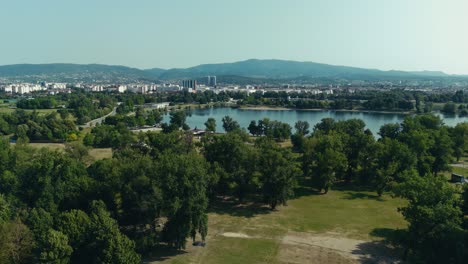 aerial view of lake jarun park with city skyline and mountain in background