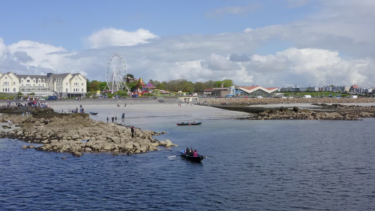 galway, la costa de irlanda y el paseo marítimo de salthill, feria de circo en la playa de las damas, barcos de currach en el agua.