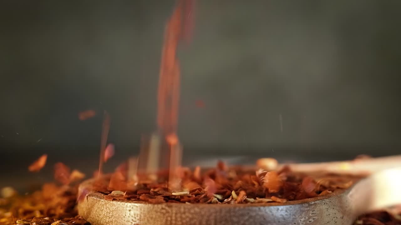 Flakes of red hot chili pepper in wooden spoon closeup on a kitchen table.