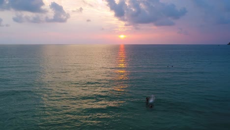 personas nadando en el océano al atardecer