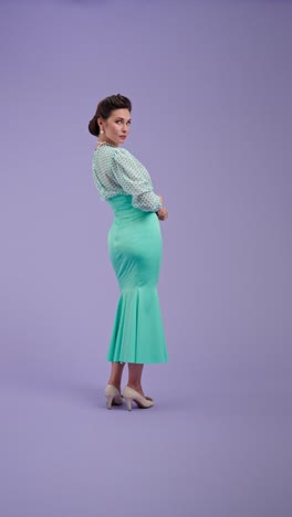 elegant woman in teal mermaid skirt and polka dot blouse posing in studio