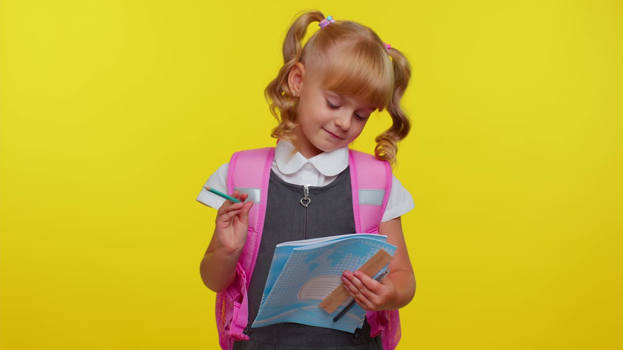 Attraktives Teenager-Mädchen in Schuluniform lächelnd, macht Bleistiftnotizen in einem Notizbuch, Bildung