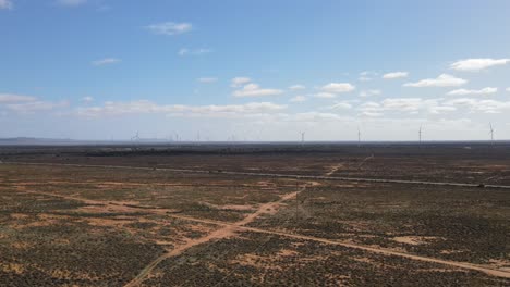 drone aerial of huge renewable energy wind farm in country australia with mountains in the background