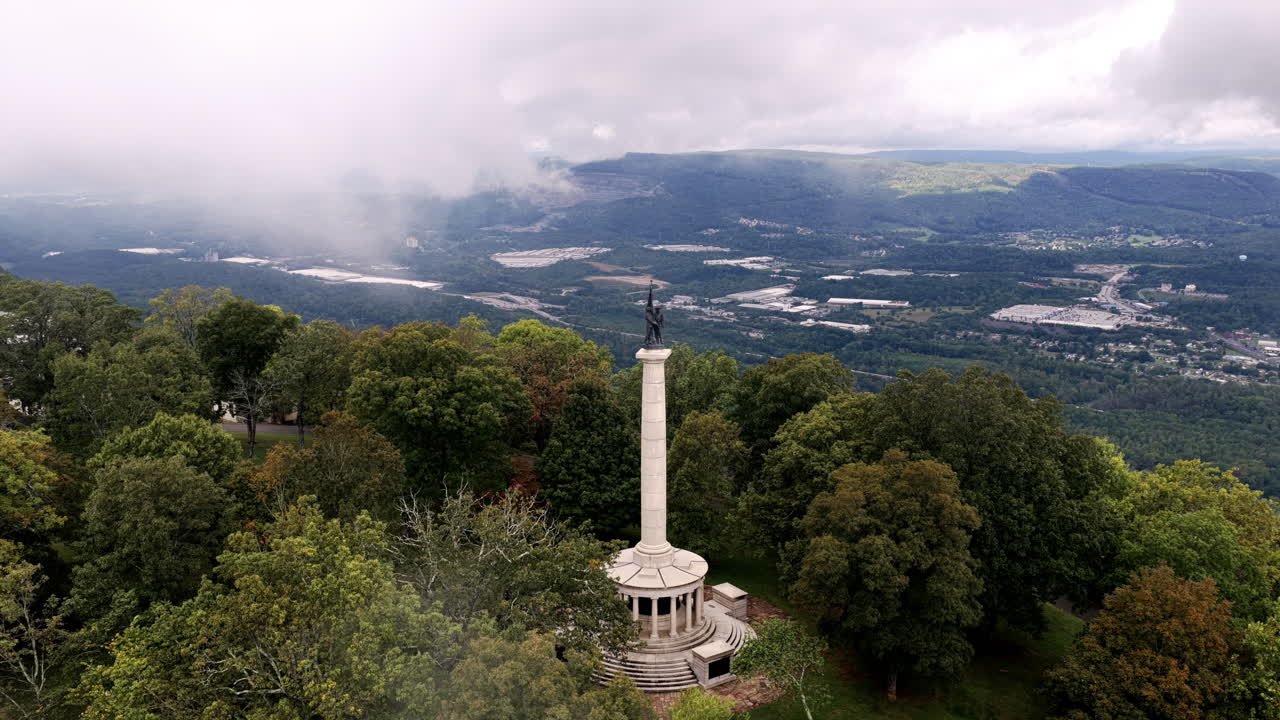 An elevated view captures the Point Park monument rising from the treetops as clouds lift to reveal the Tennessee landscape below