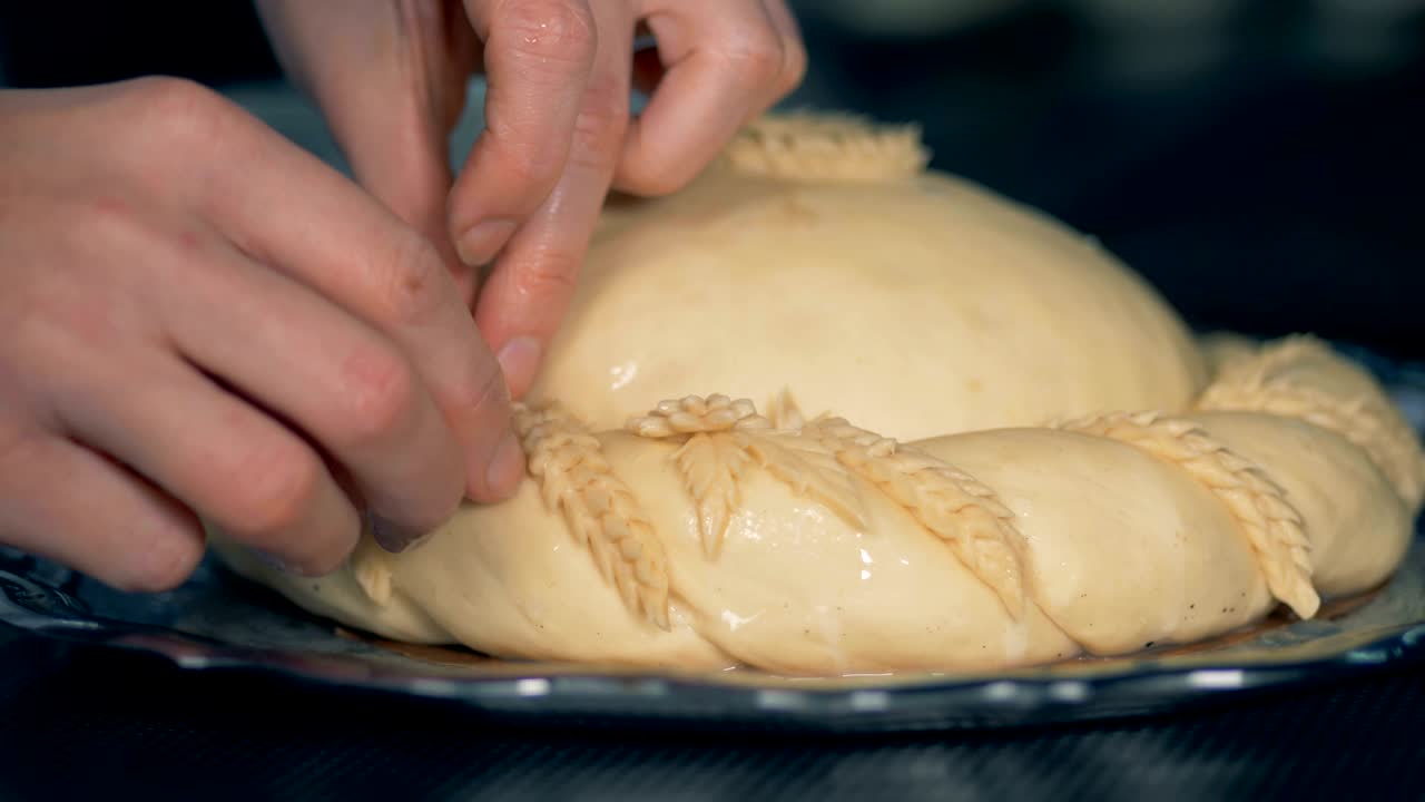 조심스러운 노동자의 손은 지 않은 큰 파이를 장식합니다.