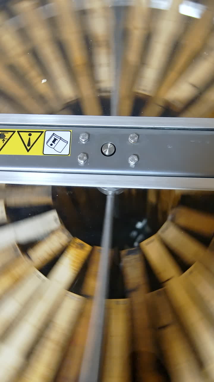 Honey extractor. Centrifuge with frames spinning inside and pumping honey. Industrial equipment to extract fresh honey from honeycombs. Top view. Vertical video