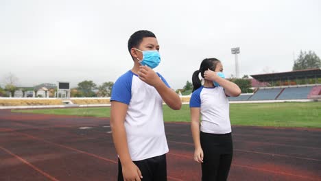 happy asian boy and girl takes off mask and running at stadium