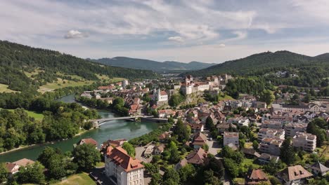 aarburg town and river aare aerial view, castle on rocky hill, meandering river, forested hills and swiss architecture under cloudy sky