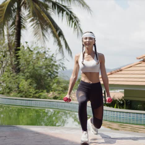 sportswoman with dumbbells walking towards camera