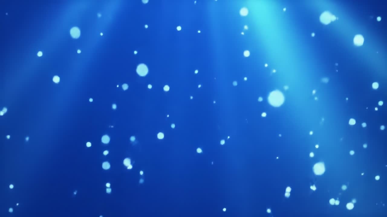 Dark blue water is filled with floating particles, creating a captivating visual effect. Rays of light penetrate the surface, adding depth to this underwater world where movement is continuous.