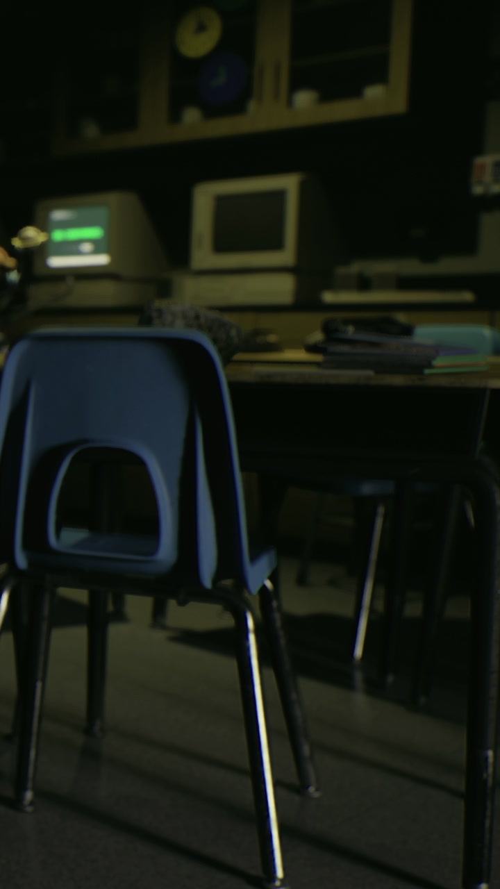 Empty chair in a classroom with old computers and desk materials close to dusk
