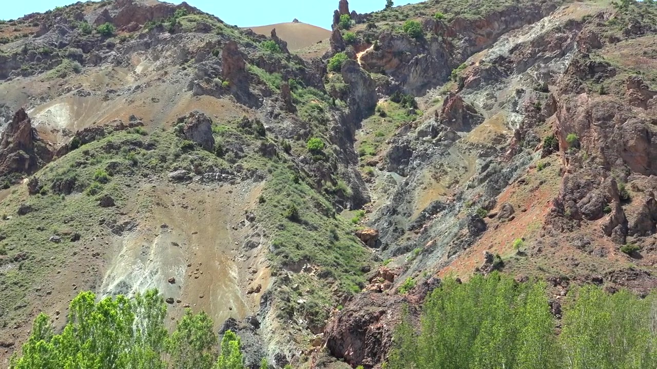 Paesaggio montano impervio con pendii rocciosi e vegetazione verde