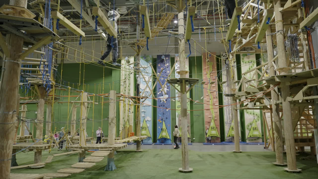 People Navigating Obstacles at an Indoor Ropes Course and Adventure Park