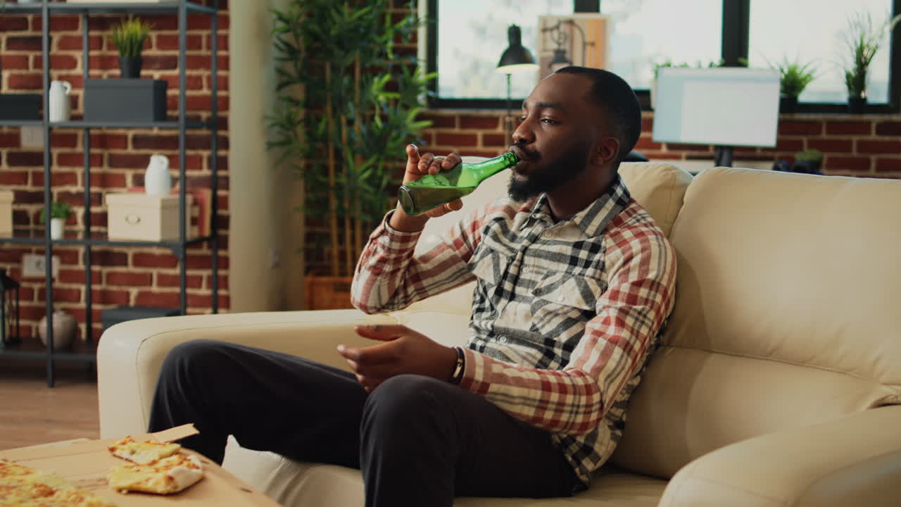 Cheerful adult taking bite of pizza at home