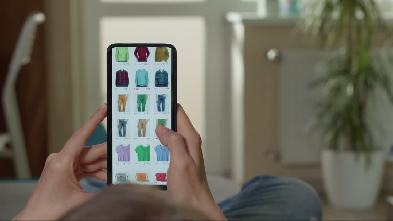 Una donna guarda lo schermo di uno smartphone con abiti alla moda. Concetto di e-commerce. Acquisto online di prodotti in negozio, marketplace, usando il telefono.