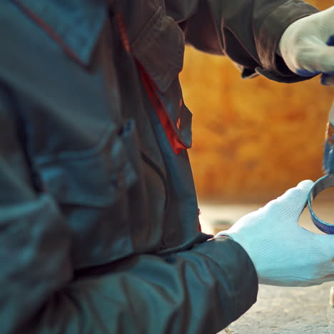 male worker uses a brush to paint a circle tool for a special section of a machine. man in working clothes paints in blue color details in the manufacturing hall. close-up