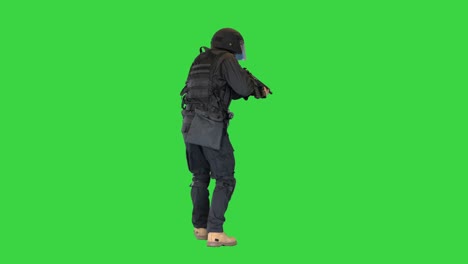 masked armed swat police officer walking and aiming with rifle on a green screen, chroma key