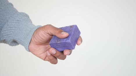 una mano sosteniendo una barra de jabón de lavanda