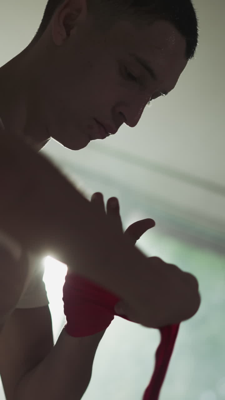 전투 체육관에서 권투를 위해 손 포장을 사용하는 전투기. 집중된 운동 선수는 무술 클럽 느린 동작에서 손바닥에 대한 보호 공급을 적용합니다. 스포츠 생활