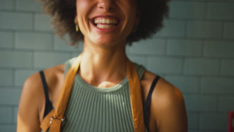portrait of smiling female owner or staff inside shop or cafe holding hot drink