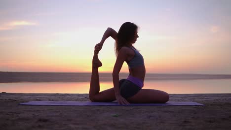 Attraktive-Yogi-Frau,-Die-Auf-Einer-Matte-Am-Meer-Trainiert.-Mischung-Aus-Yoga-Stellungen.-Morgendämmerung