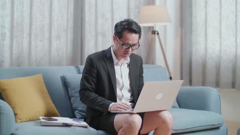 재과 쇼트를 입은 아시아 사업가 가 집 에서 노트북 으로 비디오 통화를 하고 있다