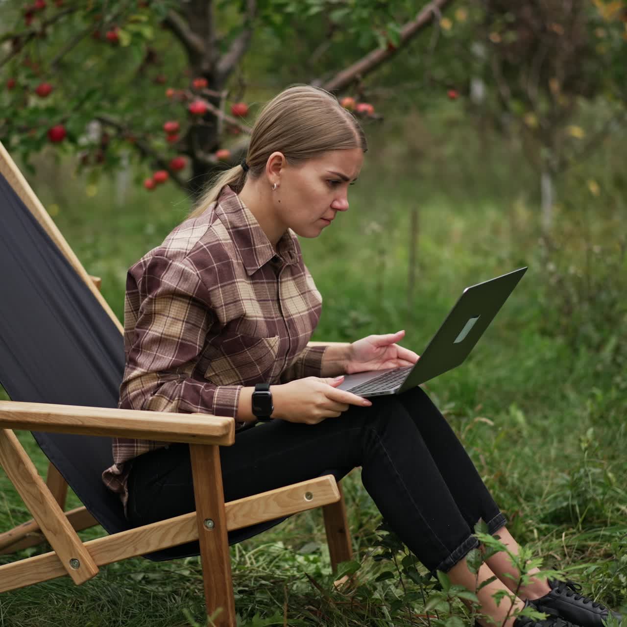 Affascinante giovane donna che lavora con il laptop in giardino. Elegante business lady con stile di vita.