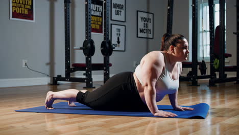 plus-size woman doing yoga in a gym