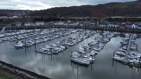 Scenic-luxurious-waterfront-harbour-apartment-village-yachts-and-sailboats-under-mountain-coastline-aerial-view-orbit-right