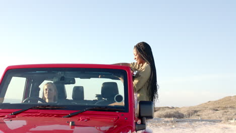 Young-African-American-woman-and-young-Caucasian-woman-enjoy-a-road-trip-on-a-road-trip,-with-copy-s