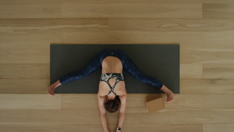 above view yoga woman practicing seated forward bend pose in workout studio enjoying healthy lifestyle meditation practice training on exercise mat