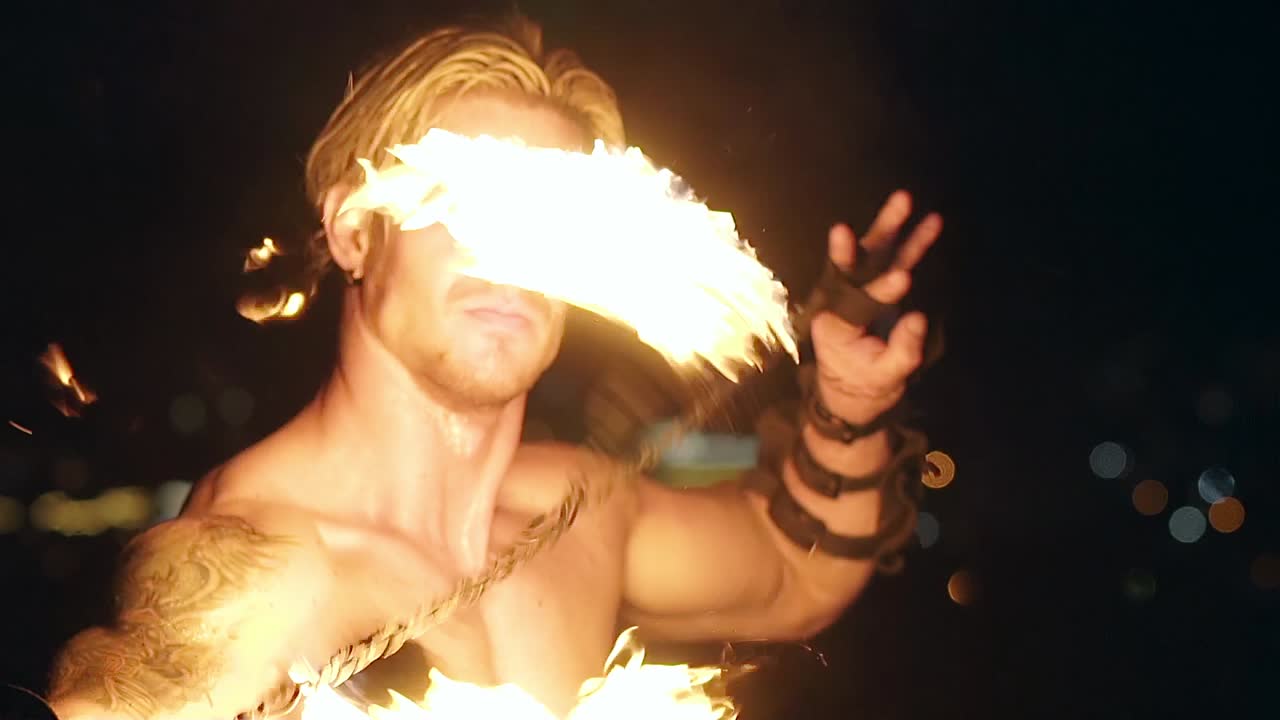 un joven rubio gira dos venenos en llamas en cámara lenta en primer plano