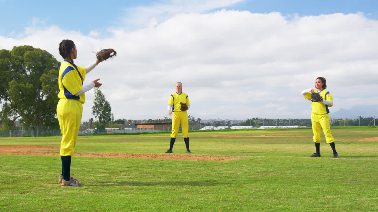 Multiracial female baseball players catching and throwing the ball on a pitch, copy space